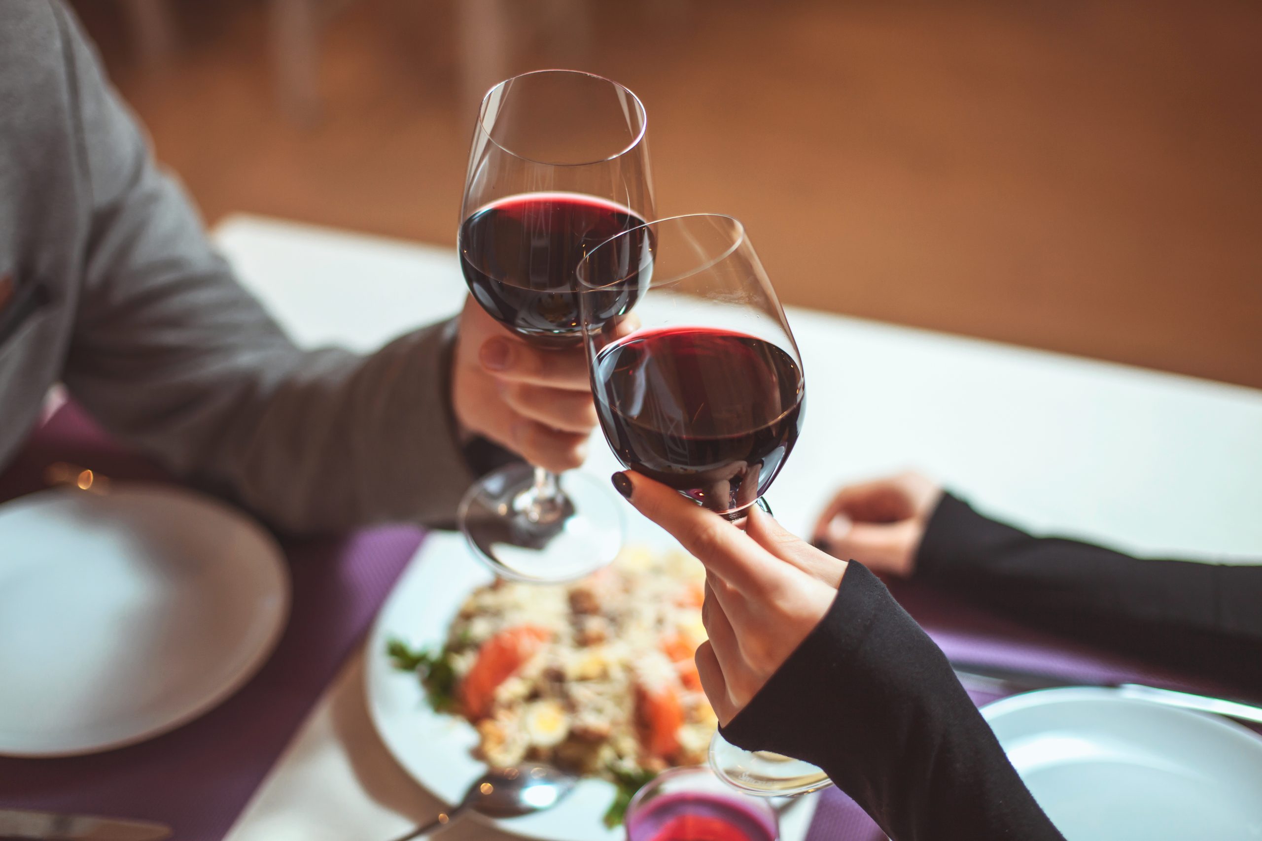 Beautiful young couple with glasses of red wine in luxury restau